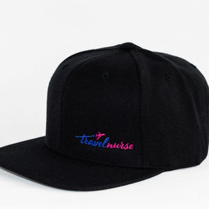 Product photo showing a black snapback with a pink and blue travel nurse logo