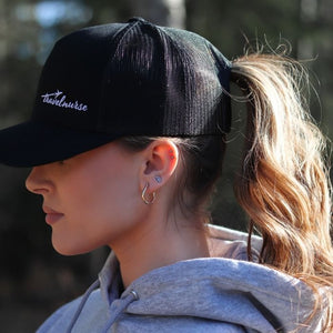 side view of a model wearing a mesh back hat with a white travel nurse logo. 