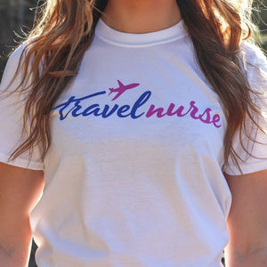 close up of a model wearing white travel nurse t shirt with blue and pink logo