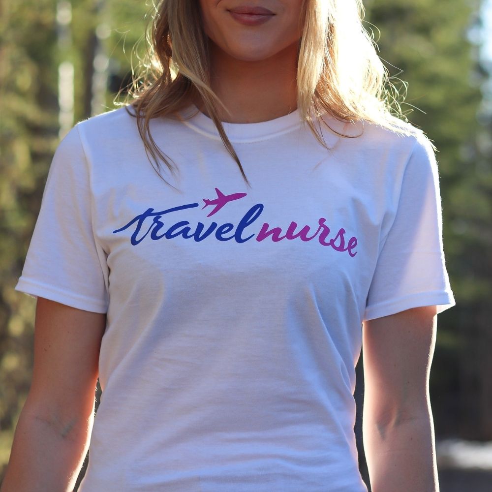 model wearing white travel nurse t shirt with blue and pink logo